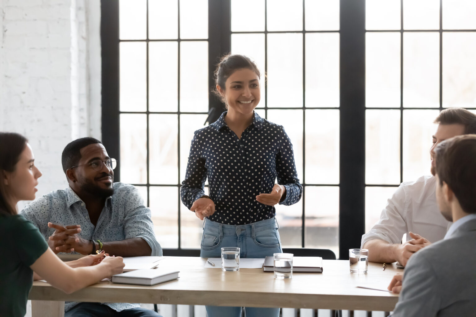 Happy Indian business leader holding corporate meeting with diverse team