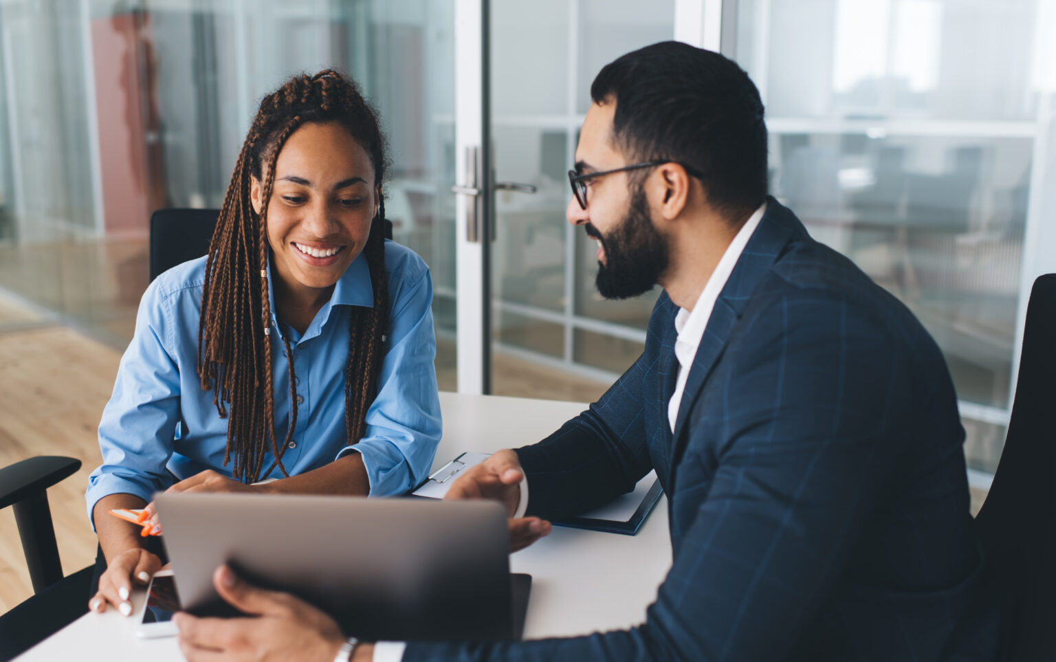 Successful business people browsing text information on corporate website using laptop computer in office interior, skilled male and female employees discussing application while making online booking