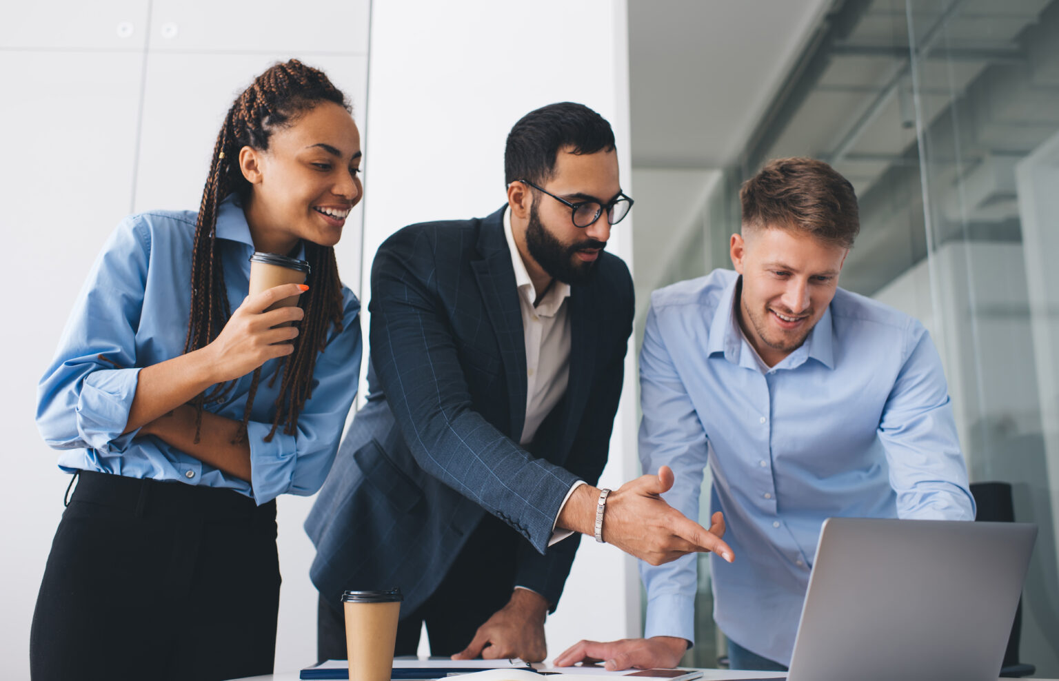 Skilled male ad female colleagues discussing business information during involved brainstorming in corporate office, diverse employees browsing website on laptop technology using WIFI internet at desk